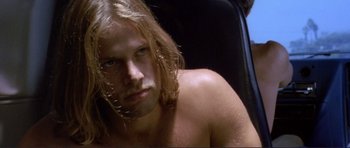 Movie still from “Point Break” (1991), directed by Kathryn Bigelow – A man with long blonde hair sitting in a car; Close Up shot, High angle