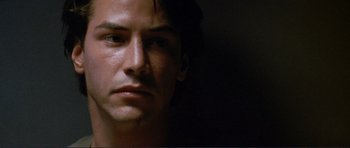 Movie still from “Point Break” (1991), directed by Kathryn Bigelow – A man's face in a dark room; Close Up shot, Low angle