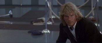 Movie still from “Point Break” (1991), directed by Kathryn Bigelow – A man in a suit and tie sitting on the ground; Close Up shot, Low angle