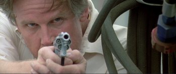 Movie still from “Point Break” (1991), directed by Kathryn Bigelow – A man holding a gun in his hands; Close Up shot, Low angle