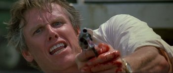 Movie still from “Point Break” (1991), directed by Kathryn Bigelow – A man is holding a gun in his hand; Close Up shot, Low angle
