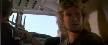 Movie still from “Point Break” (1991), directed by Kathryn Bigelow – A person with long hair in a vehicle; Close Up shot, Low angle