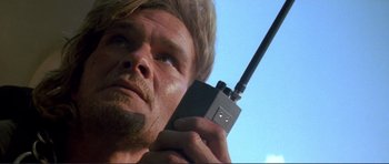Movie still from “Point Break” (1991), directed by Kathryn Bigelow – A person holding a walkie talkie; Close Up shot, Low angle