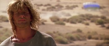 Movie still from “Point Break” (1991), directed by Kathryn Bigelow – A man with blonde hair standing in the desert; Close Up shot, Over the shoulder angle