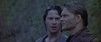 Movie still from “Point Break” (1991), directed by Kathryn Bigelow – Two men standing next to each other in the rain; Close Up shot, Over the shoulder angle