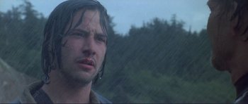 Movie still from “Point Break” (1991), directed by Kathryn Bigelow – A person in the rain with trees in the background; Close Up shot, Low angle