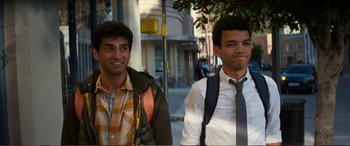 Movie still from “Pokémon: Detective Pikachu” (2019), directed by Rob Letterman – Two young men are walking down the sidewalk; Medium shot, Over the shoulder angle