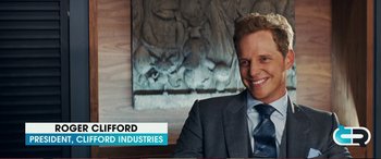 Movie still from “Pokémon: Detective Pikachu” (2019), directed by Rob Letterman – A man in a suit and tie sitting in front of a sign; Close Up shot, Over the shoulder angle