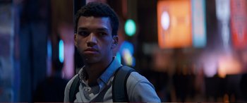 Movie still from “Pokémon: Detective Pikachu” (2019), directed by Rob Letterman – A man with a backpack standing in the street; Close Up shot, Over the shoulder angle