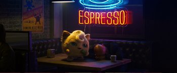 Movie still from “Pokémon: Detective Pikachu” (2019), directed by Rob Letterman – A stuffed animal sitting on top of a wooden table; Medium shot, Low angle