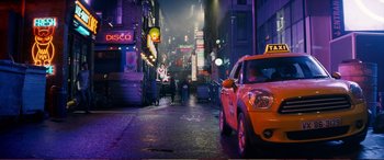 Movie still from “Pokémon: Detective Pikachu” (2019), directed by Rob Letterman – A taxi cab is parked on the side of the street; Extreme Wide shot, High angle