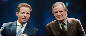 Movie still from “Pokémon: Detective Pikachu” (2019), directed by Rob Letterman – Two men in suits and ties are posing for a picture; Close Up shot, Over the shoulder angle