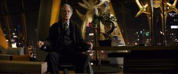 Movie still from “Pokémon: Detective Pikachu” (2019), directed by Rob Letterman – An older man in a suit sitting in front of a bonsai tree; Medium shot, Low angle