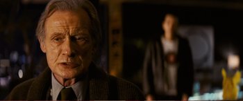 Movie still from “Pokémon: Detective Pikachu” (2019), directed by Rob Letterman – An old man in a suit and tie looking at the camera; Close Up shot, Over the shoulder angle