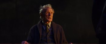 Movie still from “Pokémon: Detective Pikachu” (2019), directed by Rob Letterman – An older man wearing a sweater and a tie; Medium shot, Over the shoulder angle