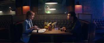 Movie still from “Pokémon: Detective Pikachu” (2019), directed by Rob Letterman – A man and a woman are sitting at a table; Medium shot, Over the shoulder angle