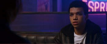 Movie still from “Pokémon: Detective Pikachu” (2019), directed by Rob Letterman – A young man sitting on a couch in a room; Close Up shot, Over the shoulder angle