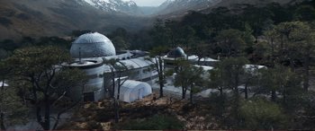 Movie still from “Pokémon: Detective Pikachu” (2019), directed by Rob Letterman – An aerial view of a building in the middle of a forest; Extreme Wide shot, High angle