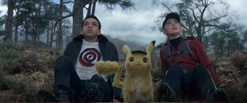 Movie still from “Pokémon: Detective Pikachu” (2019), directed by Rob Letterman – A group of people sitting next to each other in the grass; Medium shot, Low angle