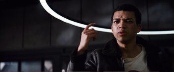 Movie still from “Pokémon: Detective Pikachu” (2019), directed by Rob Letterman – A man in a leather jacket pointing to his ear; Close Up shot, Low angle