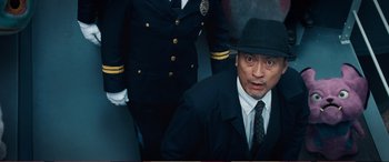 Movie still from “Pokémon: Detective Pikachu” (2019), directed by Rob Letterman – A man in a suit and hat next to two other men in suits; Close Up shot, Low angle