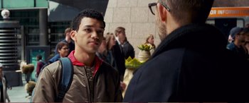 Movie still from “Pokémon: Detective Pikachu” (2019), directed by Rob Letterman – A man standing next to another man in a crowd of onlookers; Close Up shot, Over the shoulder angle