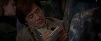 Movie still from “First Strike” (1996), directed by Stanley Tong – A man sitting on a bus looking at his phone; Close Up shot, High angle
