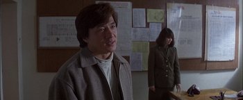 Movie still from “First Strike” (1996), directed by Stanley Tong – A man and a woman are standing in front of a bulletin board; Medium shot, Over the shoulder angle