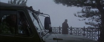 Movie still from “First Strike” (1996), directed by Stanley Tong – A man standing next to a car on a foggy day; Wide shot, Low angle