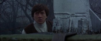 Movie still from “First Strike” (1996), directed by Stanley Tong – A man in a brown sweater looking at the camera; Close Up shot, Low angle