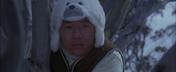 Movie still from “First Strike” (1996), directed by Stanley Tong – A man wearing a polar bear hat and a brown vest; Close Up shot, Over the shoulder angle