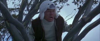 Movie still from “First Strike” (1996), directed by Stanley Tong – A man wearing a polar bear hat while sitting in a tree; Close Up shot, Low angle