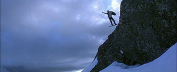 Movie still from “First Strike” (1996), directed by Stanley Tong – A man flying through the air while riding a snowboard; Extreme Wide shot, Low angle