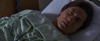 Movie still from “First Strike” (1996), directed by Stanley Tong – A man laying in a hospital bed with his eyes closed; Close Up shot, High angle