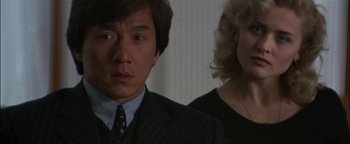 Movie still from “First Strike” (1996), directed by Stanley Tong – A man and a woman standing next to each other in a room; Close Up shot, Over the shoulder angle
