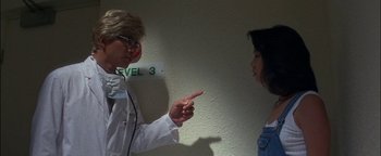 Movie still from “First Strike” (1996), directed by Stanley Tong – A woman pointing at a man wearing a lab coat; Medium shot, Over the shoulder angle