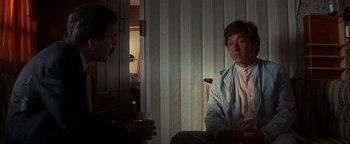 Movie still from “First Strike” (1996), directed by Stanley Tong – Two people sitting in a room talking to each other; Medium shot, Over the shoulder angle