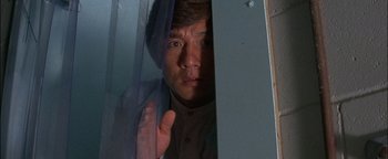 Movie still from “First Strike” (1996), directed by Stanley Tong – A man standing in front of a glass door; Close Up shot, Low angle