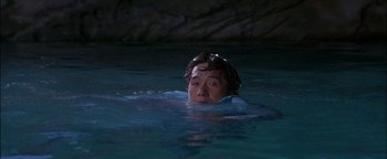 Movie still from “First Strike” (1996), directed by Stanley Tong – A man swimming in a body of water at night; Medium shot, High angle