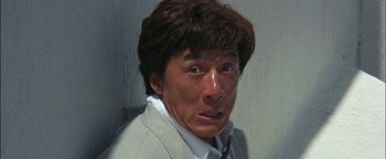 Movie still from “First Strike” (1996), directed by Stanley Tong – A person wearing a suit and tie; Close Up shot, Low angle