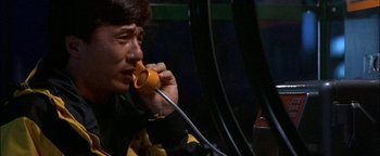 Movie still from “First Strike” (1996), directed by Stanley Tong – A man talking on a phone while sitting down; Close Up shot, High angle