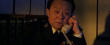 Movie still from “First Strike” (1996), directed by Stanley Tong – A man in uniform talking on a phone; Close Up shot, High angle
