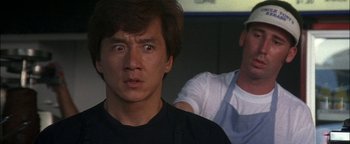 Movie still from “First Strike” (1996), directed by Stanley Tong – A young man looking at the camera while another man watches; Close Up shot, Low angle