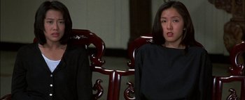 Movie still from “First Strike” (1996), directed by Stanley Tong – A woman sitting on a chair in a room; Close Up shot, Low angle