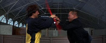 Movie still from “First Strike” (1996), directed by Stanley Tong – Two men are fighting with a sword in a building; Medium shot, Low angle