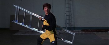 Movie still from “First Strike” (1996), directed by Stanley Tong – A man holding a ladder in his hands; Medium shot, Low angle