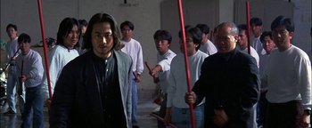 Movie still from “First Strike” (1996), directed by Stanley Tong – A group of men standing around each other; Medium shot, High angle
