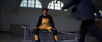 Movie still from “First Strike” (1996), directed by Stanley Tong – A man sitting on top of a metal structure; Medium shot, Low angle