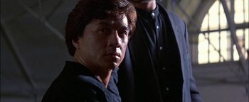 Movie still from “First Strike” (1996), directed by Stanley Tong – A person wearing a black shirt; Close Up shot, Low angle