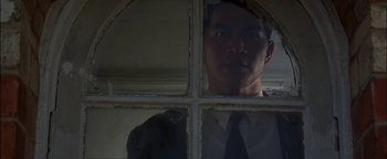 Movie still from “First Strike” (1996), directed by Stanley Tong – A man standing in front of an open window; Close Up shot, Low angle